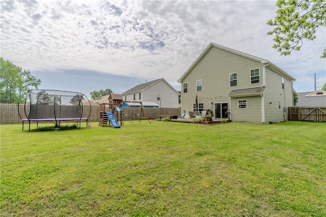 back of property with a lawn, a playground, a fenced backyard, and a trampoline