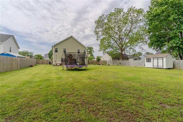 view of yard with a storage shed, a trampoline, an outbuilding, and a fenced backyard