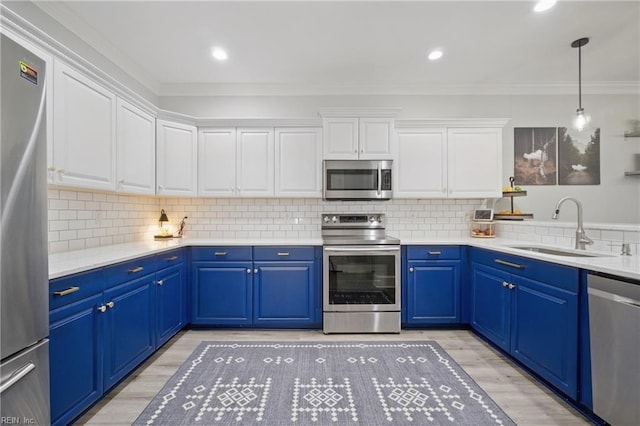 kitchen featuring white cabinets, appliances with stainless steel finishes, a sink, light wood-type flooring, and ornamental molding