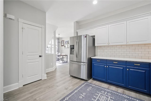 kitchen featuring stainless steel refrigerator with ice dispenser, light wood finished floors, backsplash, and white cabinetry