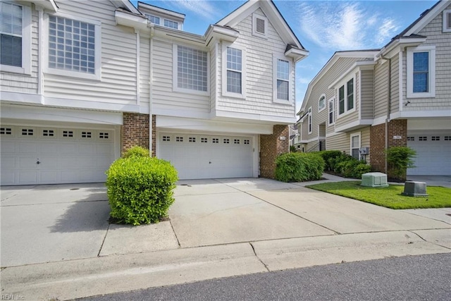 multi unit property featuring a garage, driveway, and brick siding