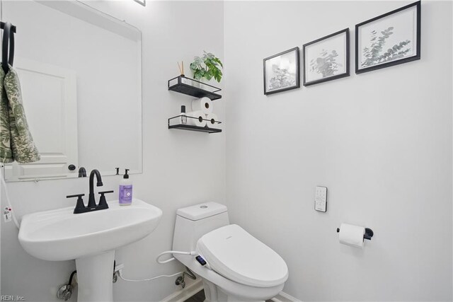 bathroom with a sink, baseboards, and toilet
