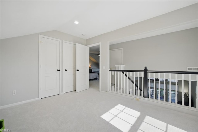 additional living space featuring baseboards, visible vents, vaulted ceiling, and light colored carpet