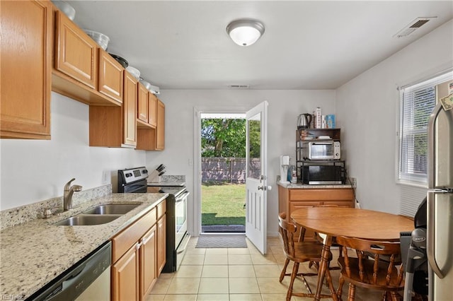kitchen featuring appliances with stainless steel finishes, light stone counters, a sink, light tile patterned floors, and visible vents