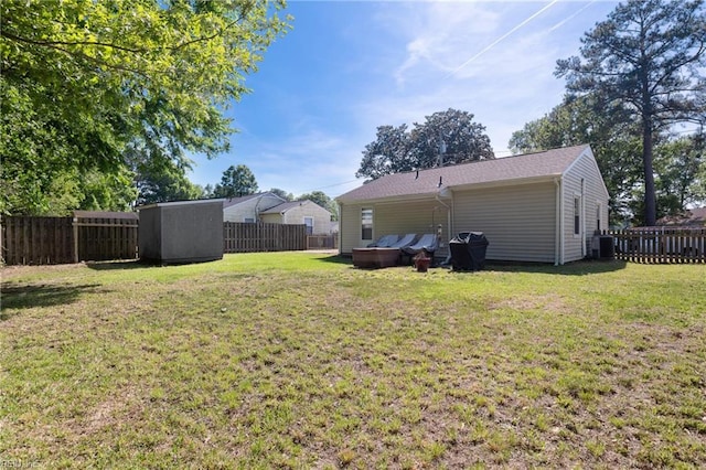 view of yard featuring central air condition unit, a fenced backyard, and a storage shed