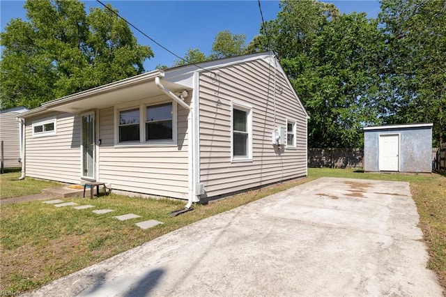 view of property exterior featuring an outbuilding, a patio area, fence, a shed, and a yard