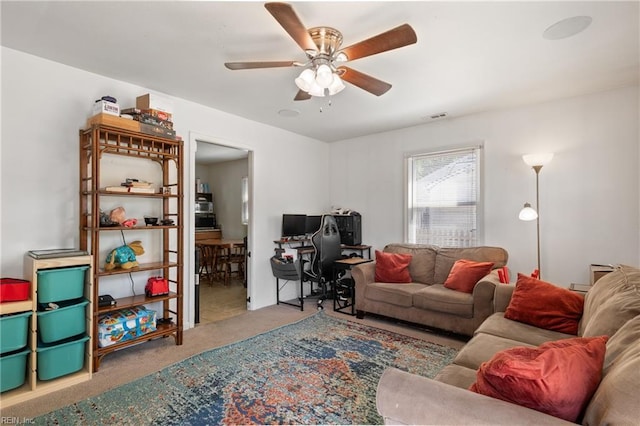carpeted living area with a ceiling fan