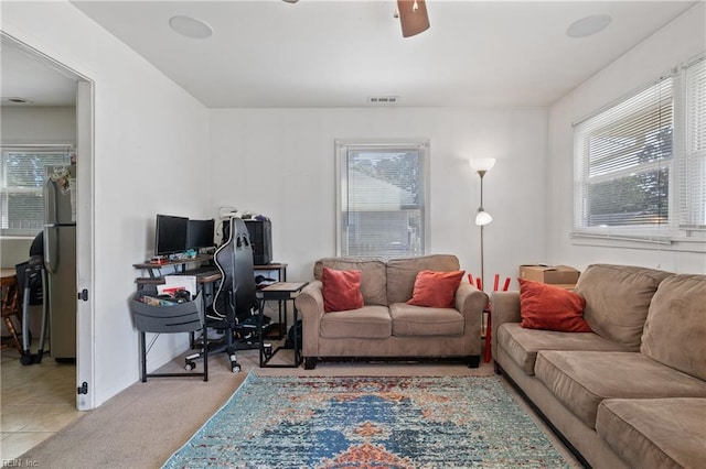 living room featuring plenty of natural light, a ceiling fan, carpet flooring, and visible vents