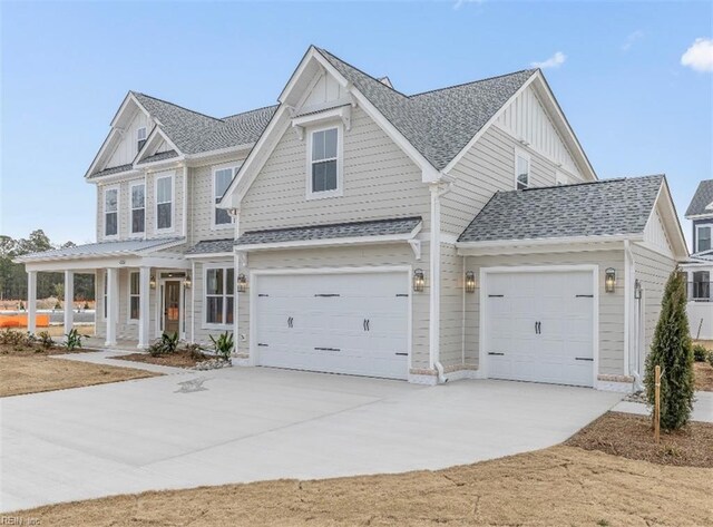 craftsman-style home with a shingled roof, a garage, board and batten siding, covered porch, and driveway