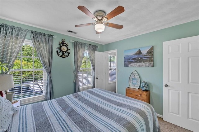 carpeted bedroom featuring visible vents, baseboards, ceiling fan, and multiple windows