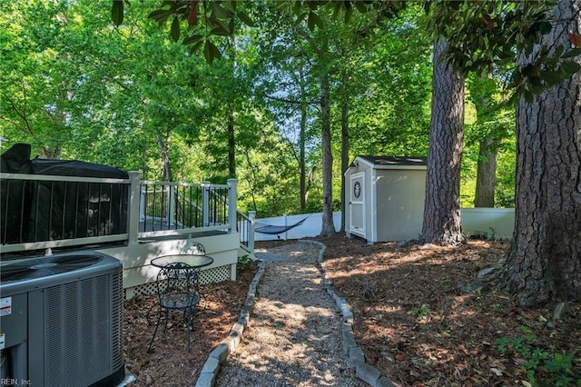 view of yard featuring a storage shed, a deck, central AC, and an outdoor structure