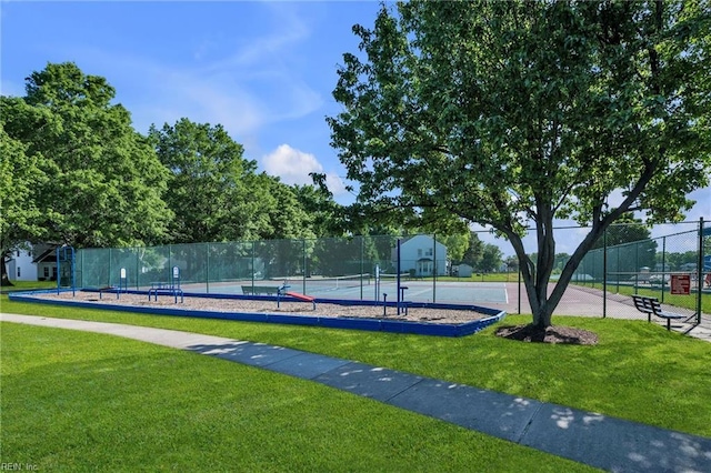 view of property's community featuring a lawn, a tennis court, and fence
