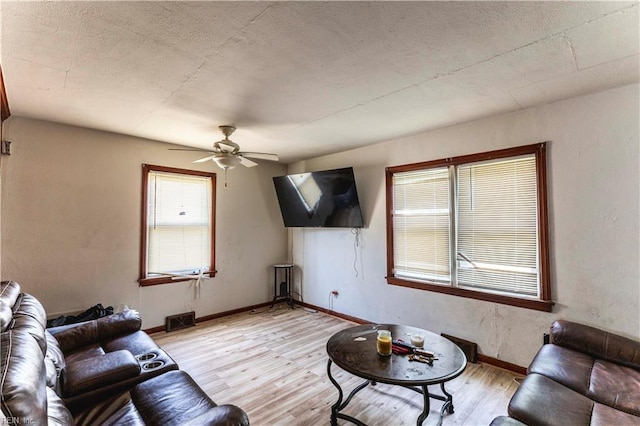 living room with baseboards, a ceiling fan, light wood-type flooring, and visible vents