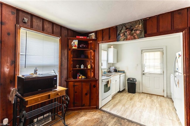 kitchen featuring open shelves, white appliances, light countertops, a sink, and light wood finished floors