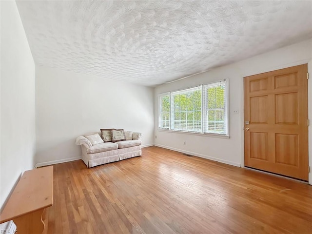sitting room with baseboards, a textured ceiling, and hardwood / wood-style flooring