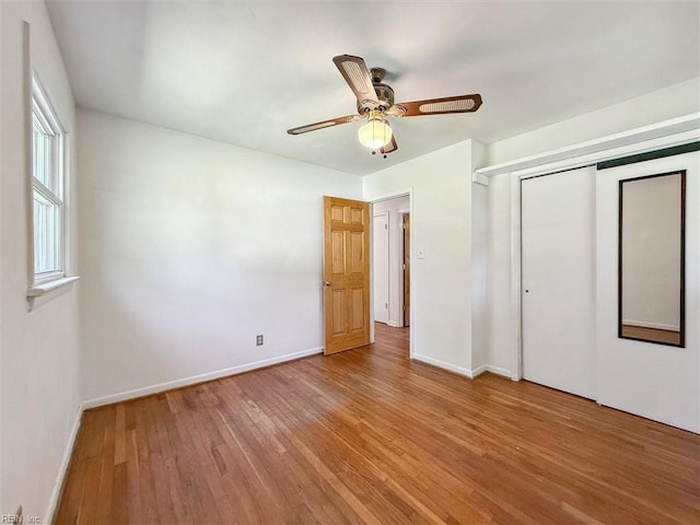 unfurnished bedroom featuring baseboards, ceiling fan, wood finished floors, and a closet