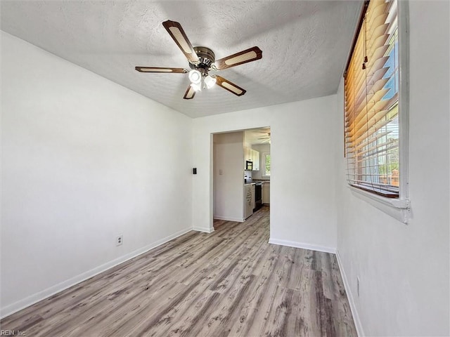 unfurnished room featuring light wood-type flooring, a textured ceiling, baseboards, and ceiling fan