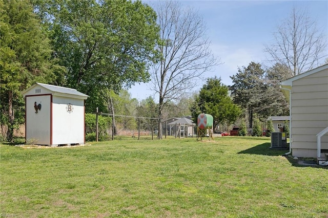 view of yard with a storage unit, an outdoor structure, central air condition unit, and fence