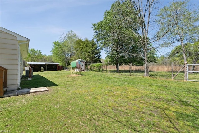 view of yard with fence, a storage unit, and an outdoor structure