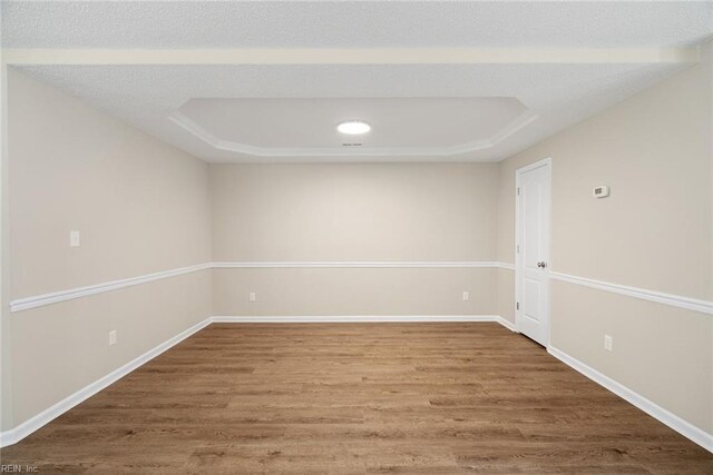 unfurnished room with baseboards, a tray ceiling, and wood finished floors