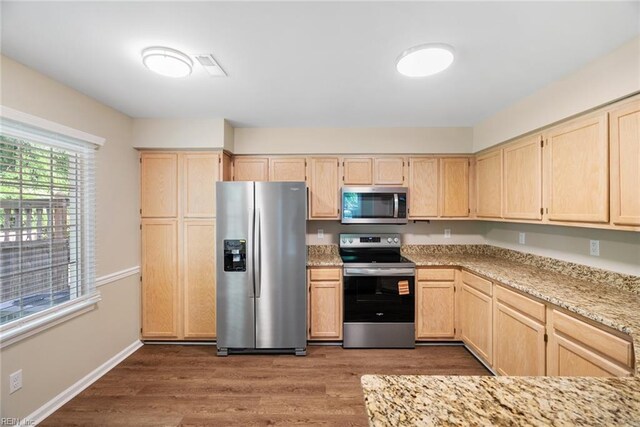 kitchen with visible vents, light brown cabinetry, light stone countertops, dark wood-style floors, and stainless steel appliances