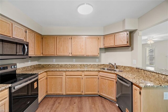 kitchen featuring a sink, light stone counters, stainless steel appliances, and light wood-style flooring