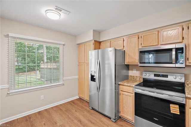 kitchen featuring visible vents, light brown cabinetry, appliances with stainless steel finishes, light wood-type flooring, and baseboards