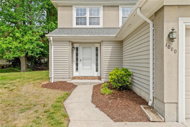 entrance to property featuring a lawn and roof with shingles
