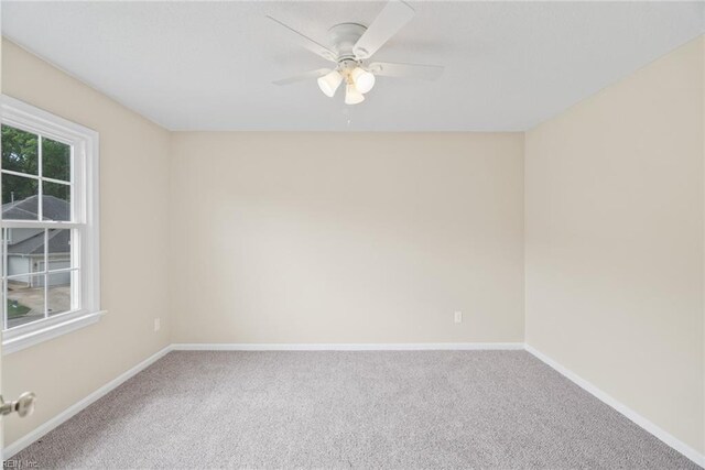 unfurnished room with a ceiling fan, baseboards, and carpet