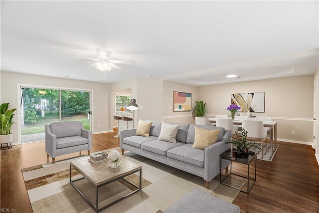 living room featuring baseboards, ceiling fan, and wood finished floors