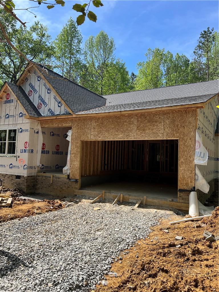 exterior space featuring a garage, roof with shingles, and driveway