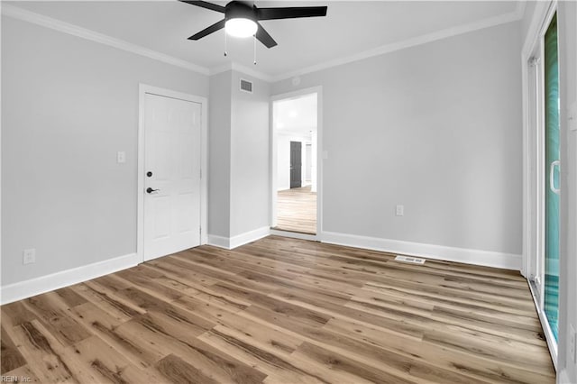 unfurnished bedroom featuring ceiling fan, baseboards, wood finished floors, visible vents, and ornamental molding
