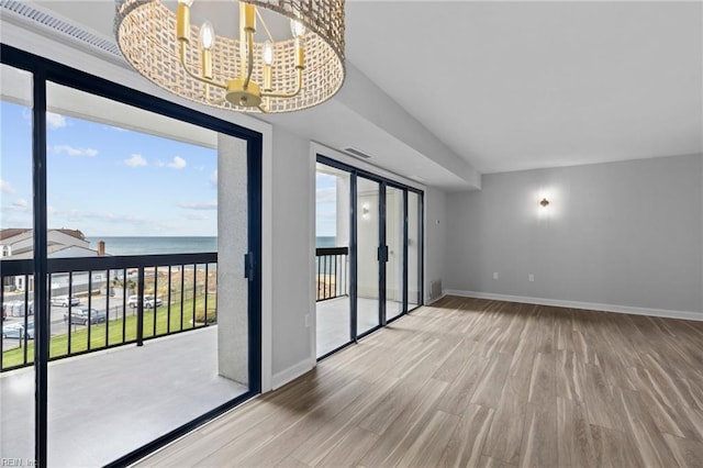 2830 Shore Dr Unit 405, Virginia Beach, VA 23451 - empty room featuring an inviting chandelier, a water view, baseboards, and wood finished floors