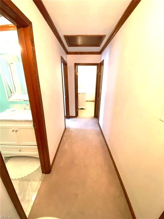 hall featuring light colored carpet, ornamental molding, and baseboards