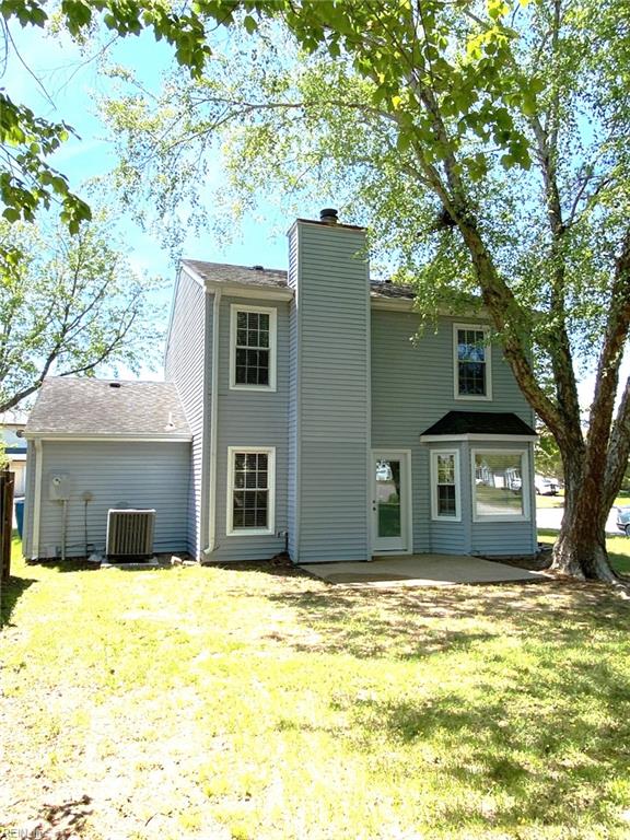 back of house with a lawn, cooling unit, a chimney, and a patio