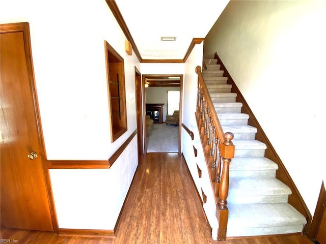 staircase featuring ornamental molding and wood finished floors