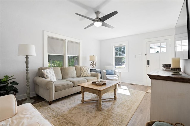 living area with ceiling fan, baseboards, and light wood-type flooring