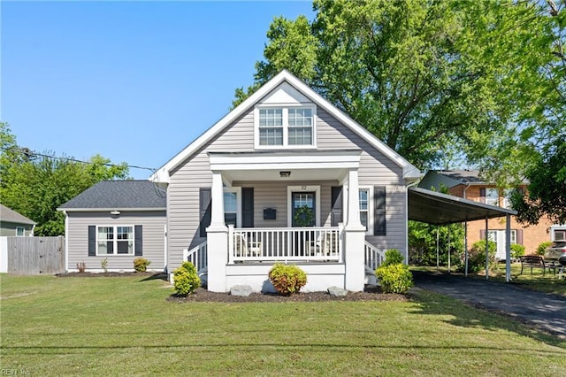 bungalow-style house featuring a front lawn, fence, an attached carport, a porch, and driveway