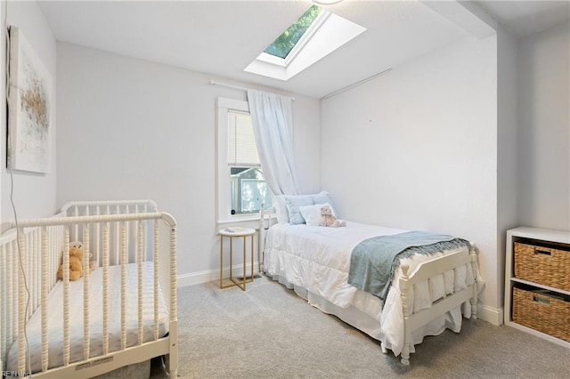 bedroom with a skylight, carpet floors, and baseboards