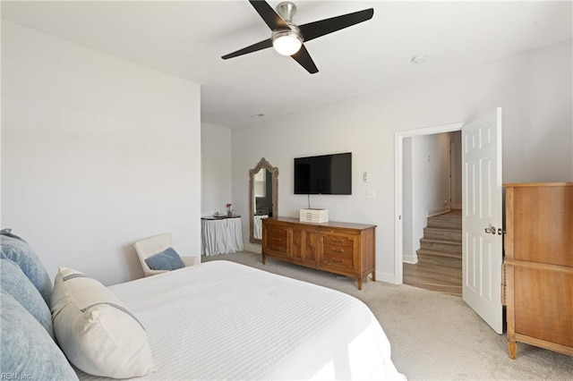 bedroom with light colored carpet, baseboards, and ceiling fan