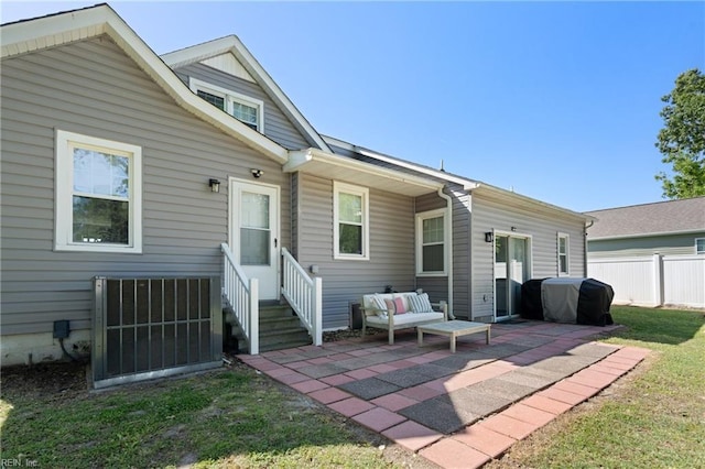 rear view of house with fence, central AC unit, an outdoor living space, a patio, and a yard