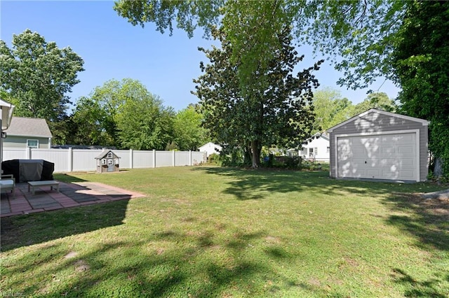 view of yard with a fenced backyard, an outbuilding, a patio area, and a garage