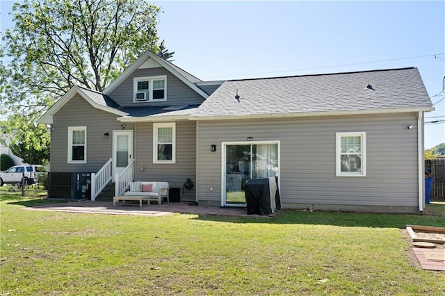 rear view of house with a lawn, roof with shingles, and a patio area
