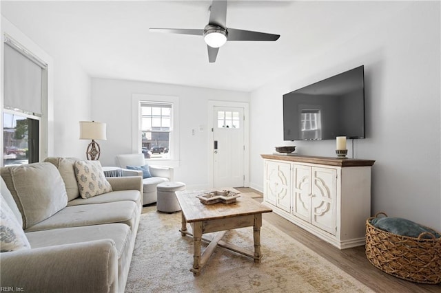 living area with baseboards, ceiling fan, and wood finished floors