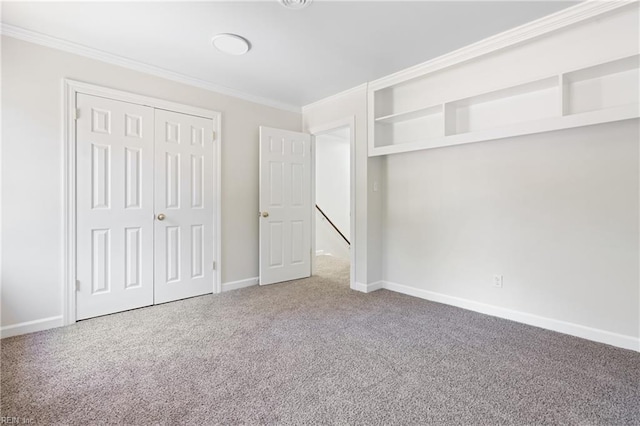 unfurnished bedroom with crown molding, baseboards, carpet flooring, and a closet