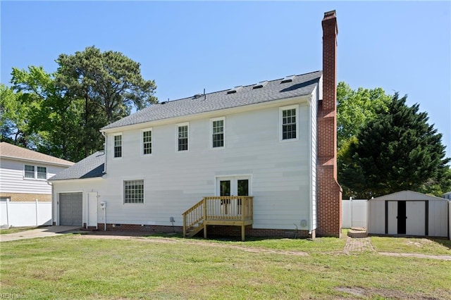 rear view of house with fence, an attached garage, a storage shed, french doors, and a yard