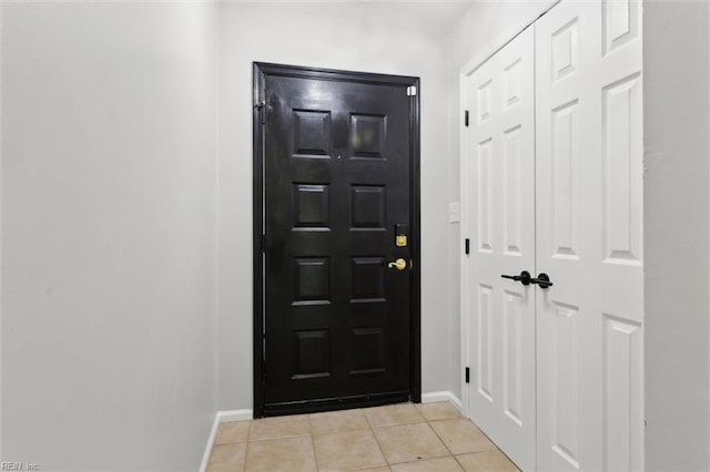 doorway featuring baseboards and light tile patterned floors