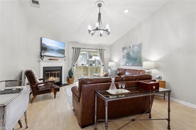 living area with a chandelier, baseboards, a fireplace with flush hearth, light wood-type flooring, and visible vents