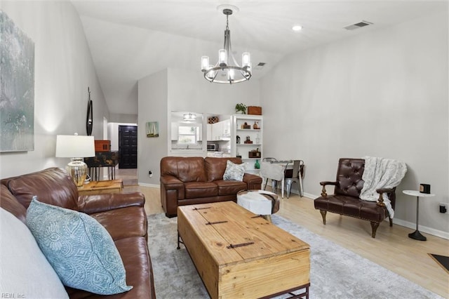 living area with visible vents, wood finished floors, baseboards, high vaulted ceiling, and a chandelier