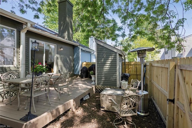wooden deck with fence, an outbuilding, outdoor dining area, and a storage unit